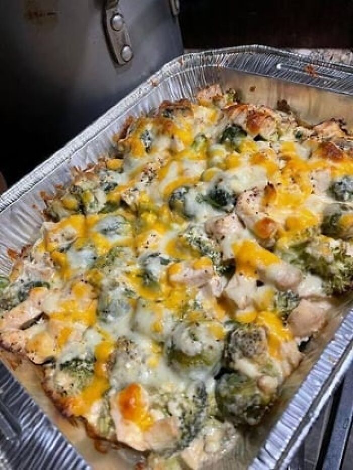 Baked cheesy broccoli and chicken casserole in a foil tray, resembling unusual shrimp jello guest dishes.