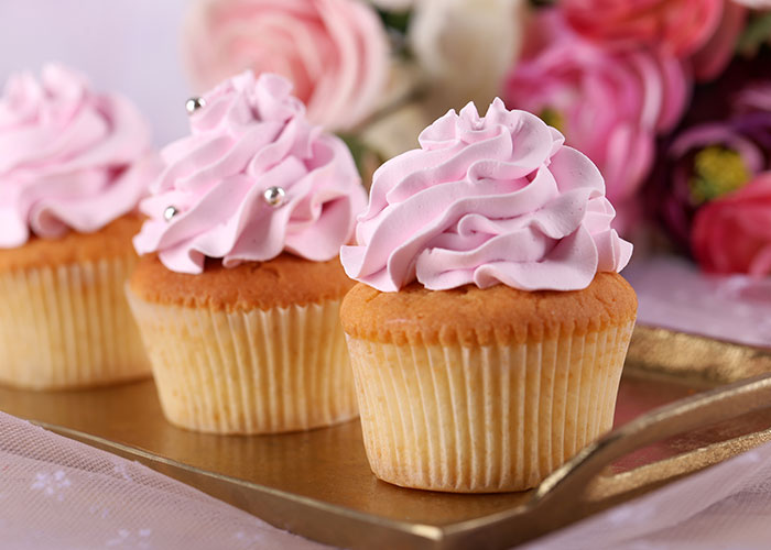 Three pink frosted cupcakes on a tray with flowers in the background representing wedding vendors and allergy concerns. Three pink frosted cupcakes on a tray with flowers in the background representing wedding vendors and allergy concerns.