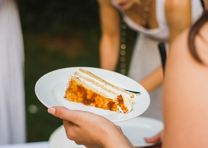 Bride holding a plate with a slice of wedding cake, highlighting wedding vendors and allergy cupcake issues. Bride holding a plate with a slice of wedding cake, highlighting wedding vendors and allergy cupcake issues.