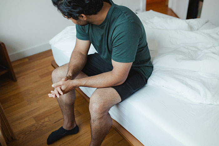 Man sitting on bed looking down, appearing uneasy after discovering hundreds of secret photos taken by girlfriend. Man sitting on bed looking down, appearing uneasy after discovering hundreds of secret photos taken by girlfriend.