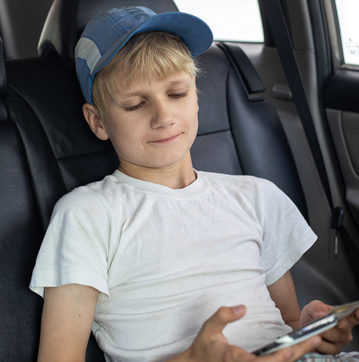 Young boy wearing a cap sitting in a car, watching a phone, related to man filming wife secretly family drama about fries.