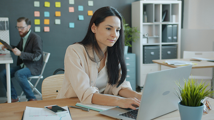 Woman focused on laptop in modern workspace, illustrating mistress turned wife facing absentee husband and family concerns.