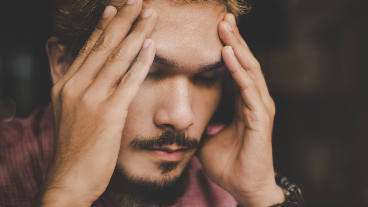 Stressed young man with eyes closed holding head, reflecting frustration related to waiter assumed 40 change was tip.