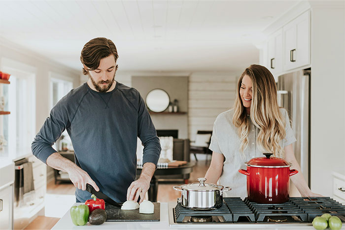 A man chopping onions while a woman looks on in a bright kitchen illustrating cooking smarter with kitchen cheats.