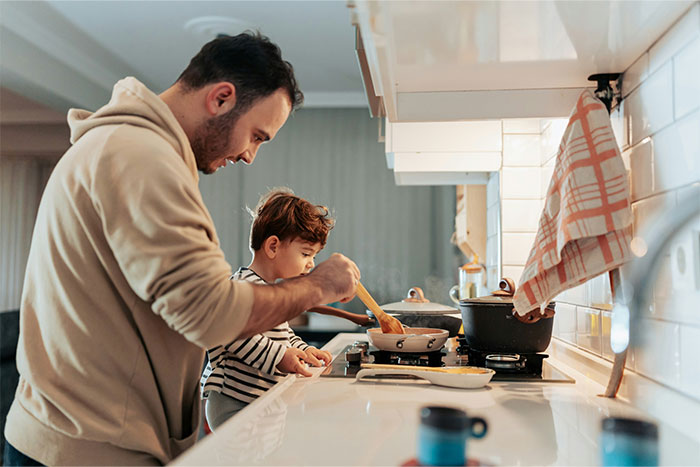 Man cooking with young child in kitchen, demonstrating smarter cooking and kitchen cheats for blowing dry chicken.