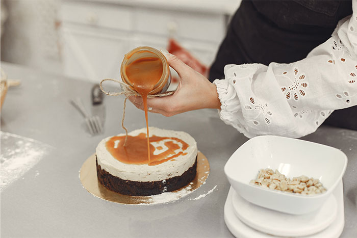 Pouring caramel sauce over a cake in a kitchen, demonstrating clever cooking and creative kitchen hacks.
