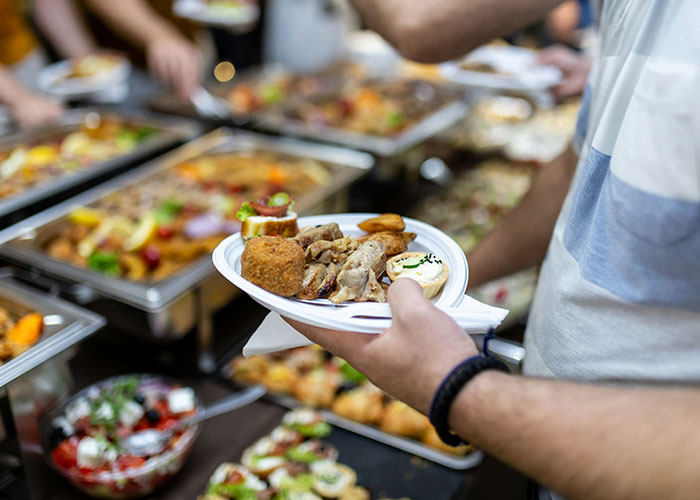 Person holding a plate of assorted food at a buffet, unrelated to medical examinations uncovering disturbing truths.