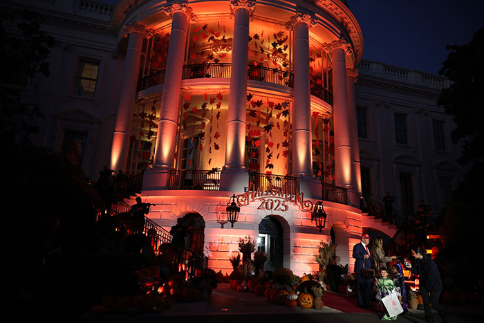 White House Halloween display illuminated with orange lights and autumn decorations during evening event in 2023. White House Halloween display illuminated with orange lights and autumn decorations during evening event in 2023.