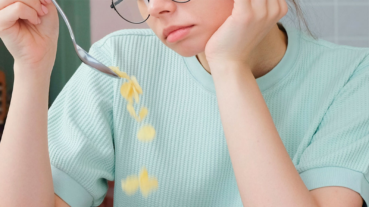 Woman in glasses and green shirt looking unhappy while dropping uneaten food from a spoon, related to daughter not eating meals