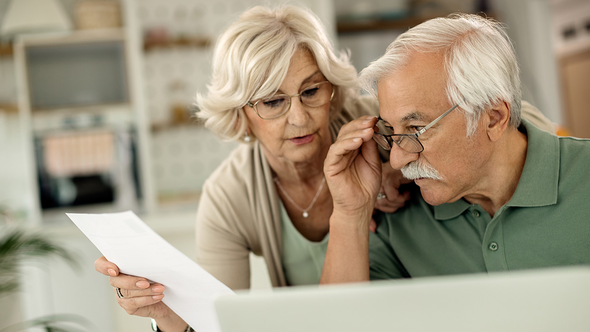 Middle-aged couple reviewing documents together, addressing husband feeling emasculated over wife earning more money.