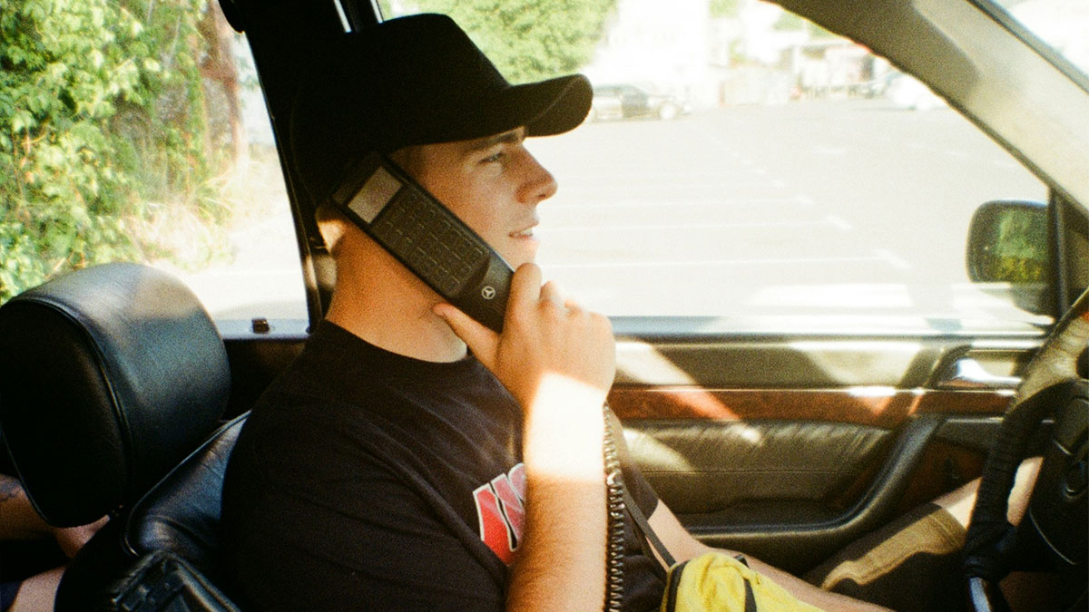 Young man in a car using a retro phone, illustrating chaotic breakup stories shared by exes in candid moments.