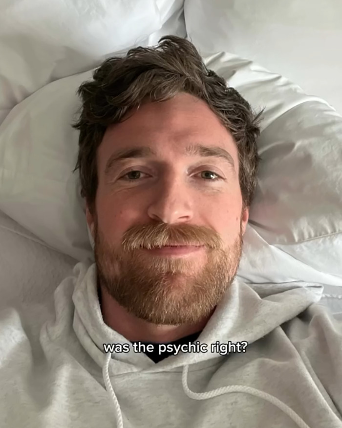 A bearded man lying on a bed wearing a gray hoodie with text about a psychic drawing changing love life. A bearded man lying on a bed wearing a gray hoodie with text about a psychic drawing changing love life.