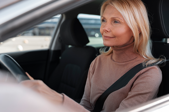 Middle-aged woman driving a car, representing a mom standing her ground on balancing autistic student’s needs and injured child. Middle-aged woman driving a car, representing a mom standing her ground on balancing autistic student’s needs and injured child.