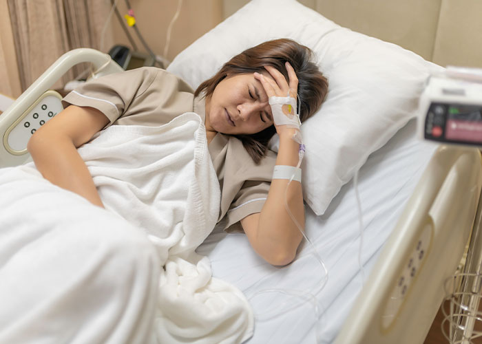 Woman in hospital bed recovering from surgery, showing distress and lack of support while caring for two kids. Woman in hospital bed recovering from surgery, showing distress and lack of support while caring for two kids.