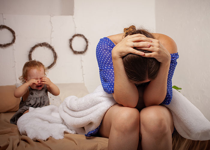 Woman feeling overwhelmed and unsupported with two kids at home after surgery, breaking down emotionally on the bed. Woman feeling overwhelmed and unsupported with two kids at home after surgery, breaking down emotionally on the bed.