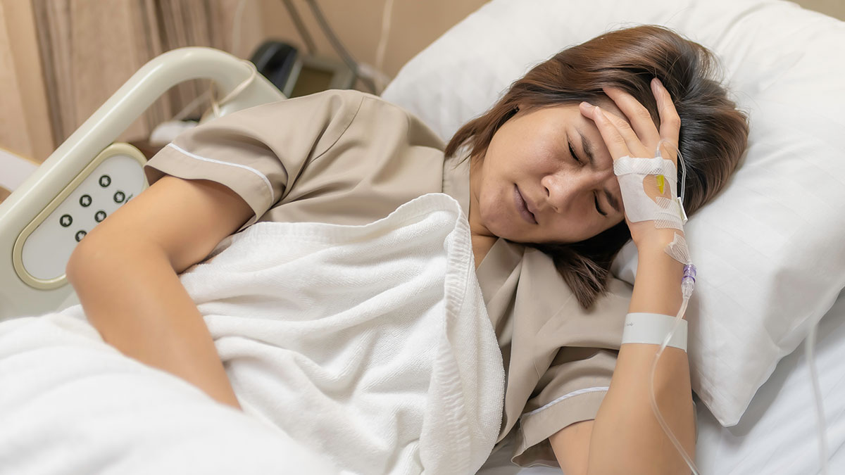 Woman in hospital bed recovering from surgery, showing pain and lack of support during recovery with two kids.
