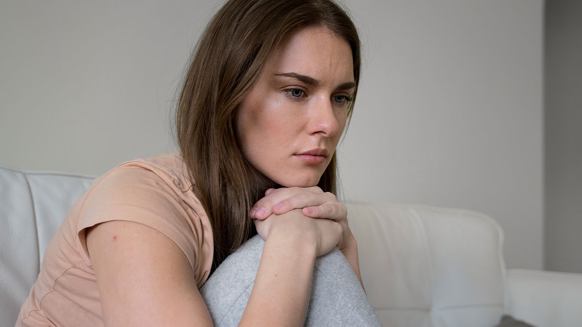 Woman sitting alone looking sad and thoughtful, reflecting on husband leaving due to deaf baby and blaming wife