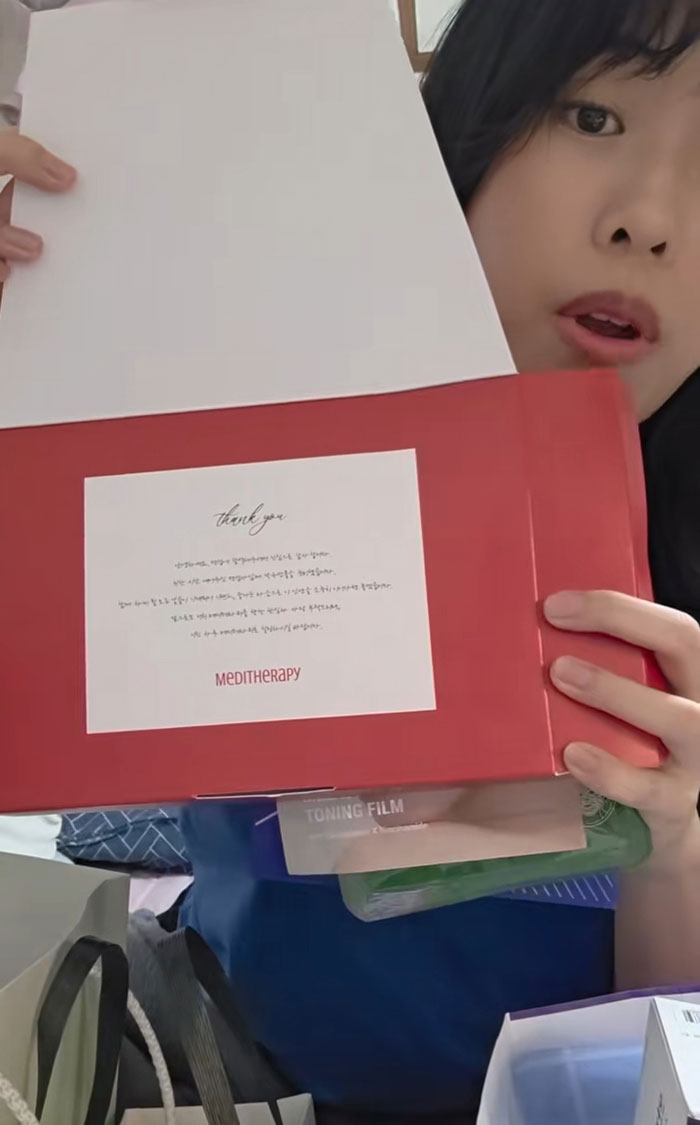 Woman showing gifts received while interviewing for jobs in Korea, featuring skincare and beauty products in a red box. Woman showing gifts received while interviewing for jobs in Korea, featuring skincare and beauty products in a red box.