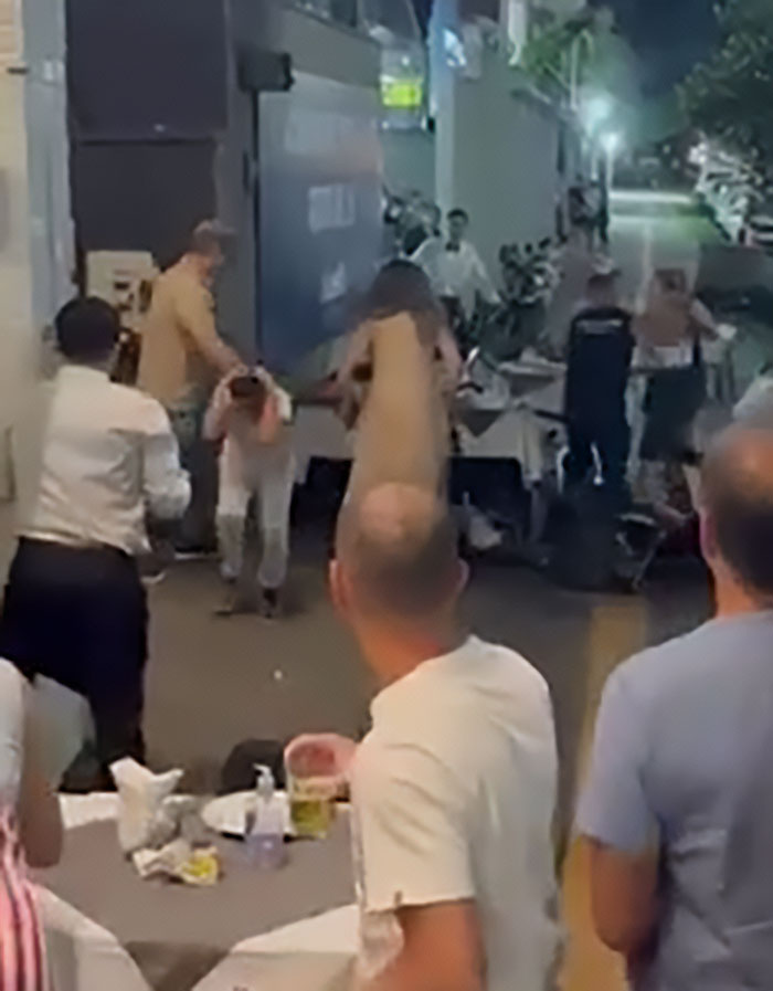 Man punches woman after she throws chair at child in a viral street altercation witnessed by bystanders at night. Man punches woman after she throws chair at child in a viral street altercation witnessed by bystanders at night.