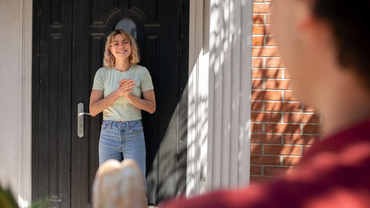 Young homeowners standing at their door enjoying privacy in their yard and pool, causing neighbor upset about fenced land.
