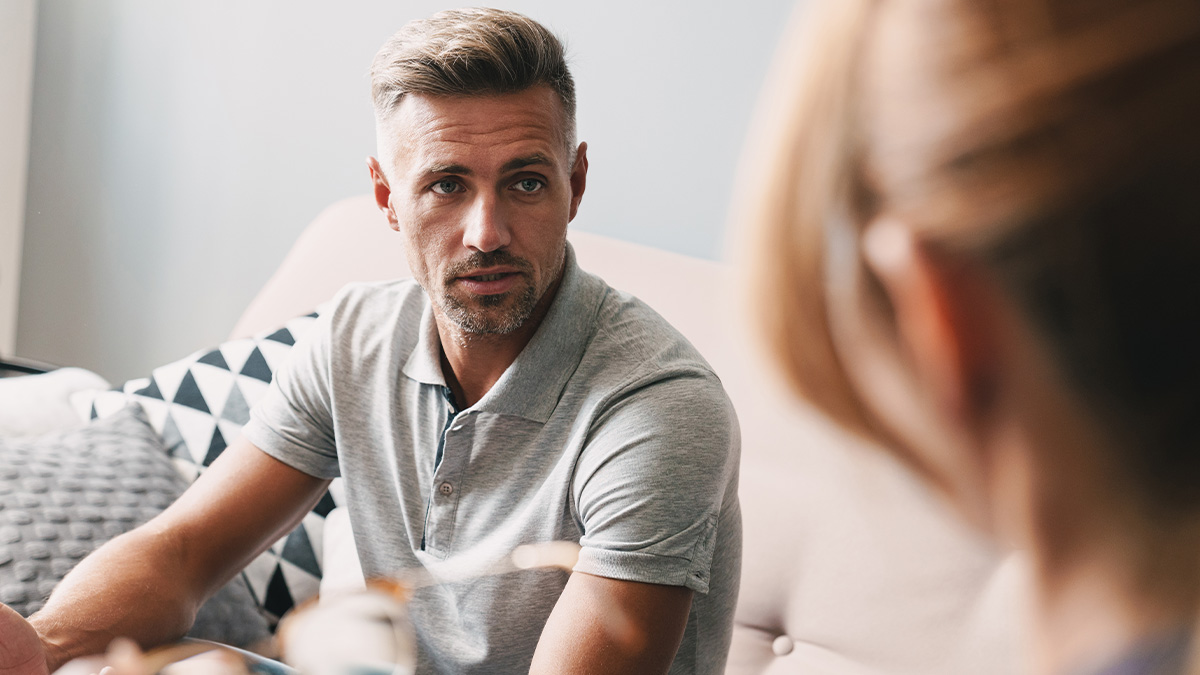 Man looking concerned while wife throws tantrum over stepson inheritance details at home.