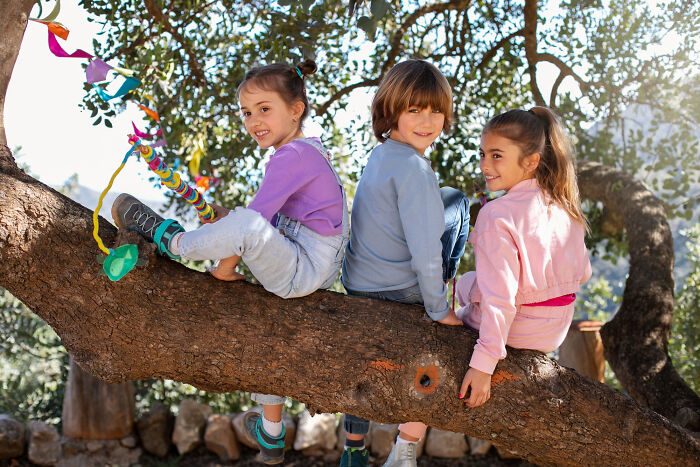 Three children sitting on a tree branch enjoying outdoor fun before Halloween experiences turned into a nightmare.