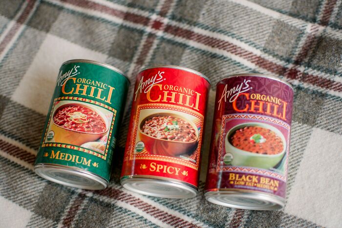 Three cans of Amy’s Organic Chili in medium, spicy, and black bean varieties on a plaid blanket.
