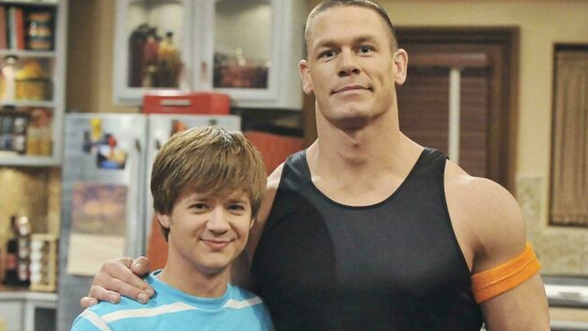 Two actors posing on a sitcom set, representing bad movie details discussed in an online group.