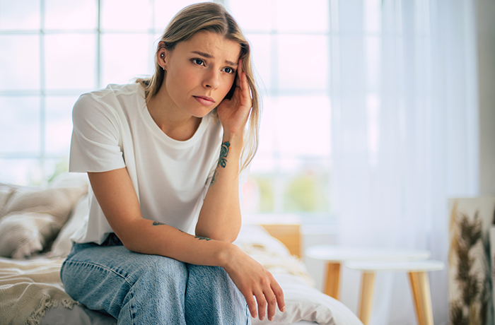 Young woman looking worried and stressed at home, reflecting the impact of false accusations on her babysitting job.