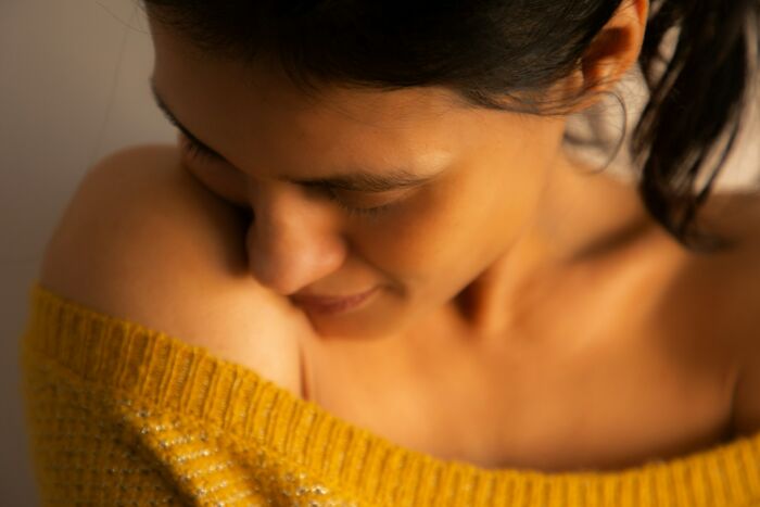 Close-up of a woman in a cozy yellow sweater, reflecting on relationship advice for couples in a warm, intimate setting.