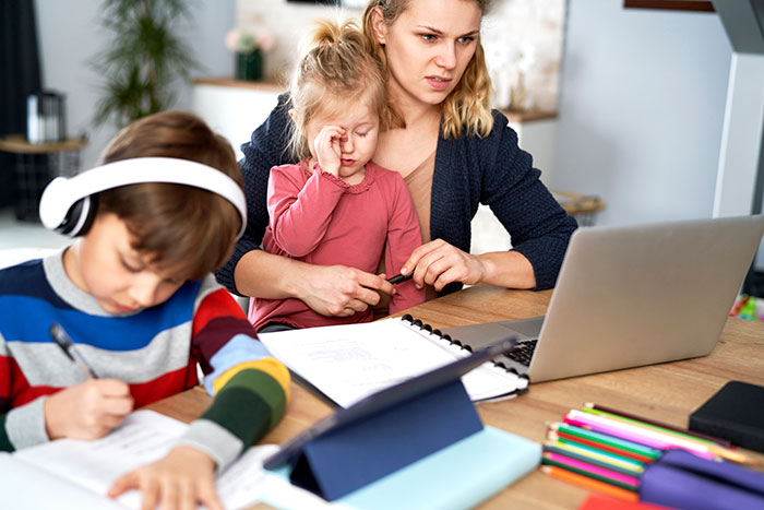 Frustrated mom multitasking with children at table, highlighting challenges of relying on sister as free babysitter. Frustrated mom multitasking with children at table, highlighting challenges of relying on sister as free babysitter.