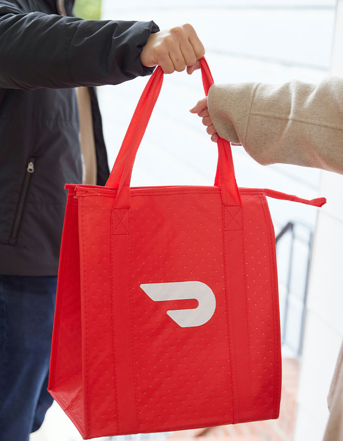 DoorDash driver handing over a red delivery bag while being involved in arrest after recording customer video incident.
