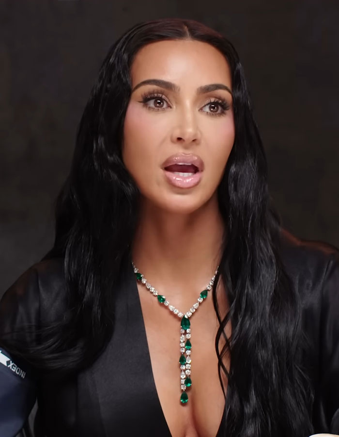 Kim Kardashian speaking in a video, wearing a black outfit and emerald necklace, discussing excuses for failing the bar exam.