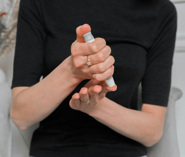 Woman squeezing insulin pen, illustrating consequences of eating what she shouldn't and affecting coworker.