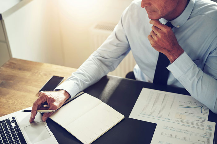 Man in a dress shirt and tie reading a handbook at desk, discovering a perfect loophole about time off from boss. Man in a dress shirt and tie reading a handbook at desk, discovering a perfect loophole about time off from boss.