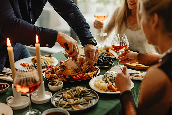 People enjoying a Thanksgiving dinner with wine and traditional dishes, highlighting a woman upset about planning assumptions. People enjoying a Thanksgiving dinner with wine and traditional dishes, highlighting a woman upset about planning assumptions.