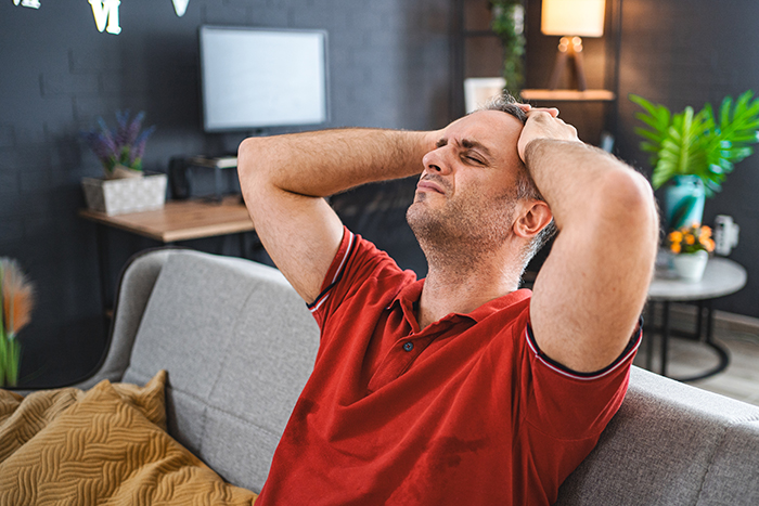A frustrated man sitting on a couch with hands on his head, reflecting on boyfriend opens relationship with no dates. A frustrated man sitting on a couch with hands on his head, reflecting on boyfriend opens relationship with no dates.