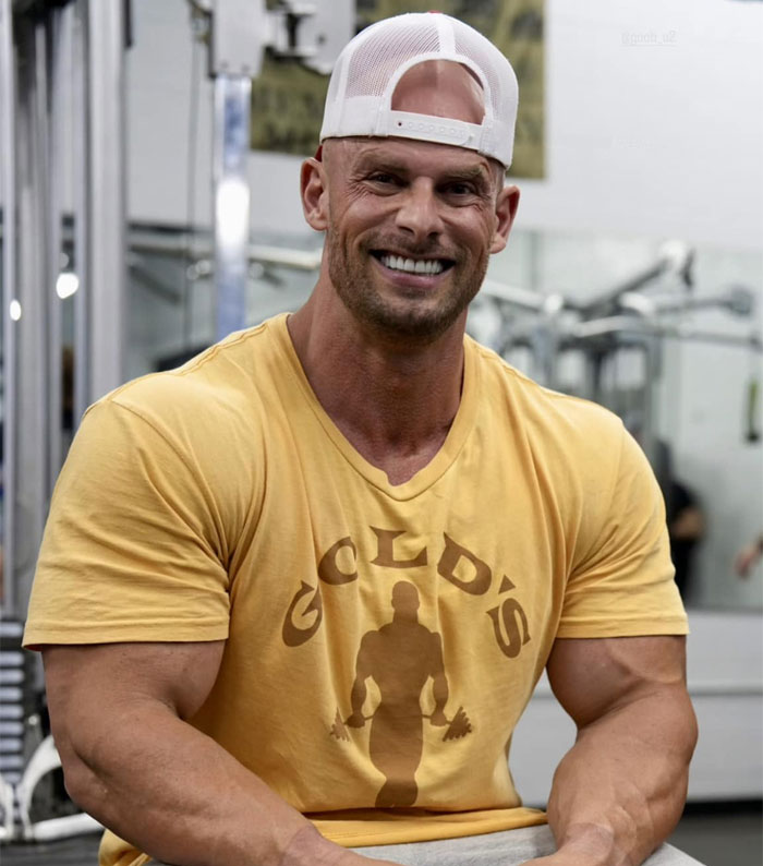 Joey Swoll smiling at the gym, wearing a Gold's Gym shirt while sitting near workout equipment. Joey Swoll smiling at the gym, wearing a Gold's Gym shirt while sitting near workout equipment.