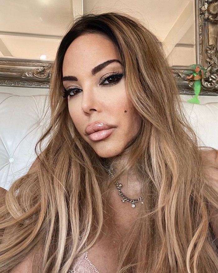 Woman with long hair and makeup posing indoors, related to fake plastic surgeon and botched silicone injections case. Woman with long hair and makeup posing indoors, related to fake plastic surgeon and botched silicone injections case.