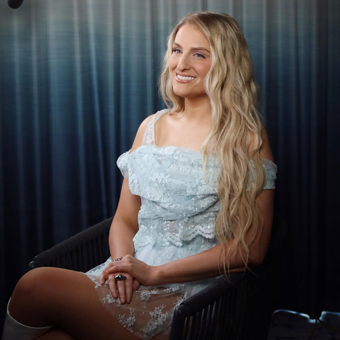 Meghan Trainor sitting in a chair wearing a light blue lace dress showing off her new look and hairstyle.