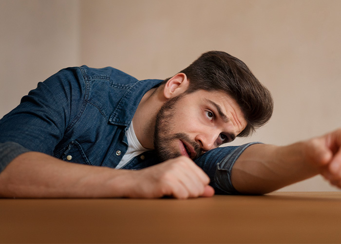 Man in a denim shirt looking exhausted and reflective, illustrating feelings of regret and parenting challenges.