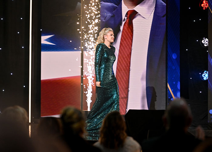 Erika Kirk walking on stage in a sparkling green dress, gestures sparking wild conspiracy theories about her acting. Erika Kirk walking on stage in a sparkling green dress, gestures sparking wild conspiracy theories about her acting.