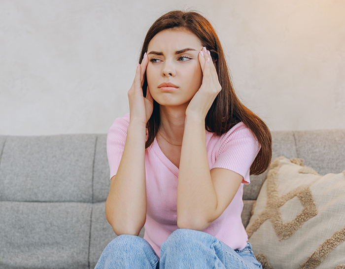 Woman feeling hurt and upset sitting on a couch, reflecting on partner’s first birth support experience without her