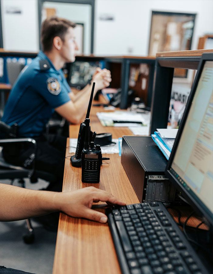 Police officers working at desks in station, featuring radio communication device and computer keyboard in focus.
