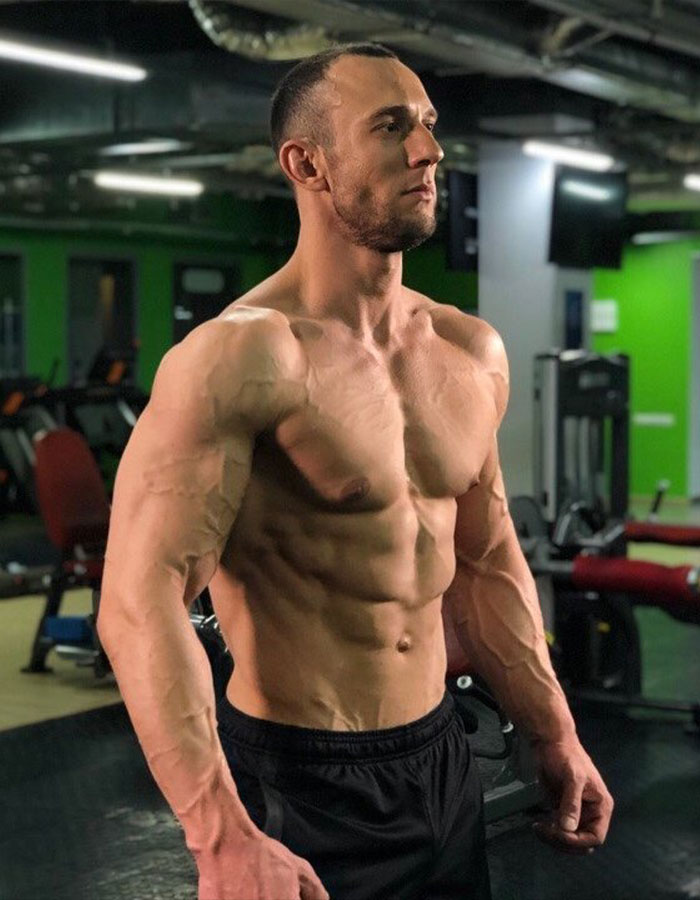 Muscular fitness coach posing confidently in gym, highlighting toned physique and vascular definition during workout session. Muscular fitness coach posing confidently in gym, highlighting toned physique and vascular definition during workout session.