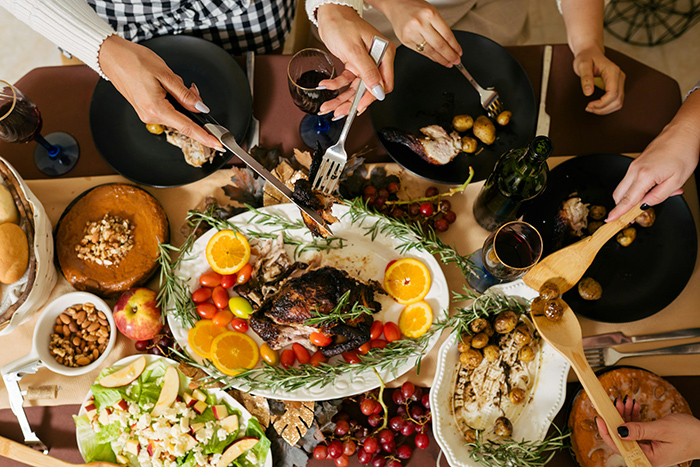 Family sharing Thanksgiving dinner with roast turkey and side dishes, highlighting in-laws making fun of woman during holiday meal.