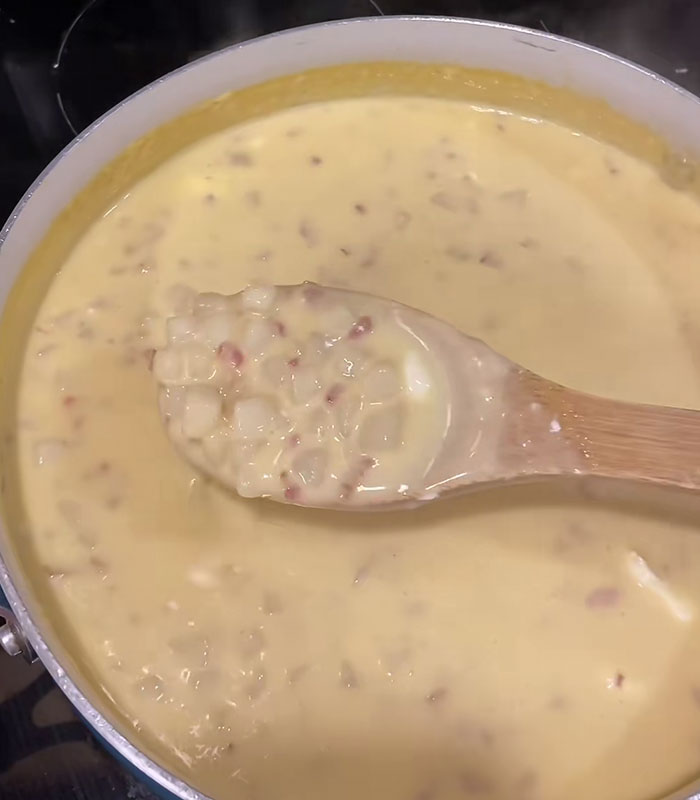 Thick creamy American corn cheese sauce with bacon bits stirred in a pot on a wooden spoon, wild food creation Thick creamy American corn cheese sauce with bacon bits stirred in a pot on a wooden spoon, wild food creation