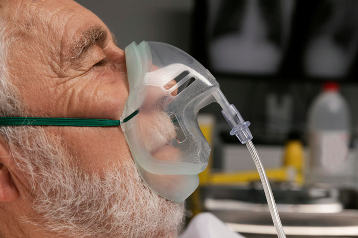 Elderly patient wearing oxygen mask in hospital setting with funny patients’ comments breaking serious vibe.