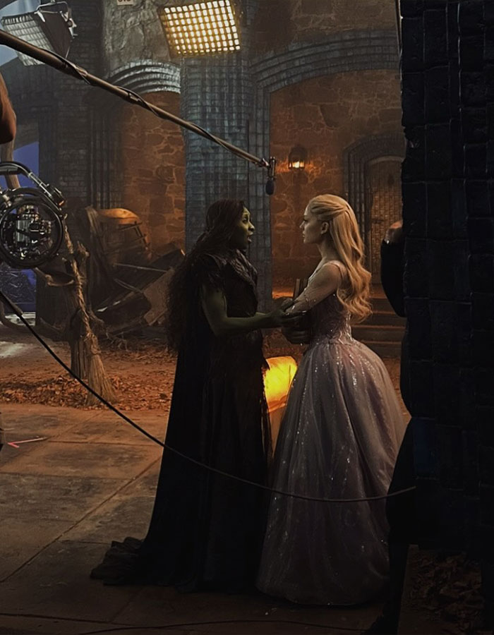 Ariana Grande and Cynthia Erivo in character on set during filming, preparing for a scene in a medieval setting. Ariana Grande and Cynthia Erivo in character on set during filming, preparing for a scene in a medieval setting.