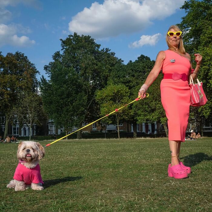 Woman and her dog both wearing matching bright pink outfits, showcasing pets and their humans looking alike outdoors.
